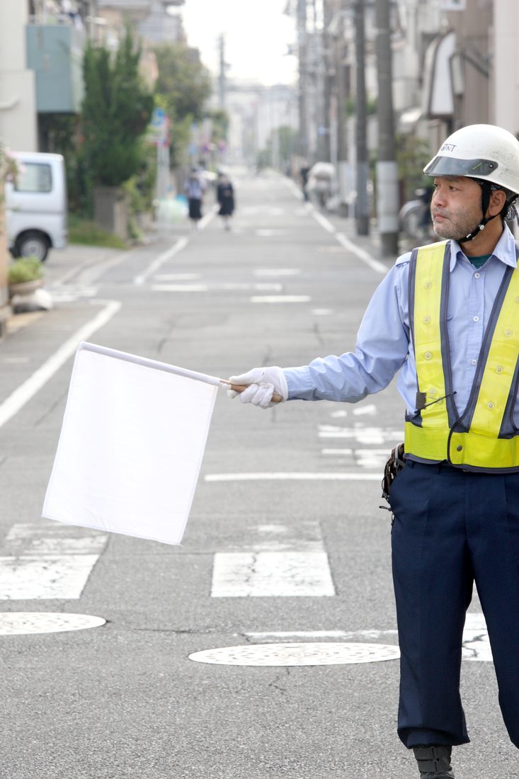 交通誘導の現場で車両を誘導するJNT Securityの警備員